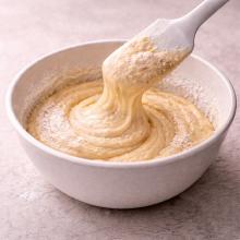 Thick pale batter folding slowly back from a spatula into the bowl