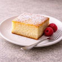Slices of tray bake with a light dusting of icing sugar on a white plate