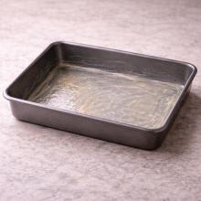 A buttered rectangular pan on pale linen