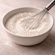 A bowl of flour with a whisk