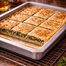 Spanakopita resting, steam gone, clean slicing lines forming